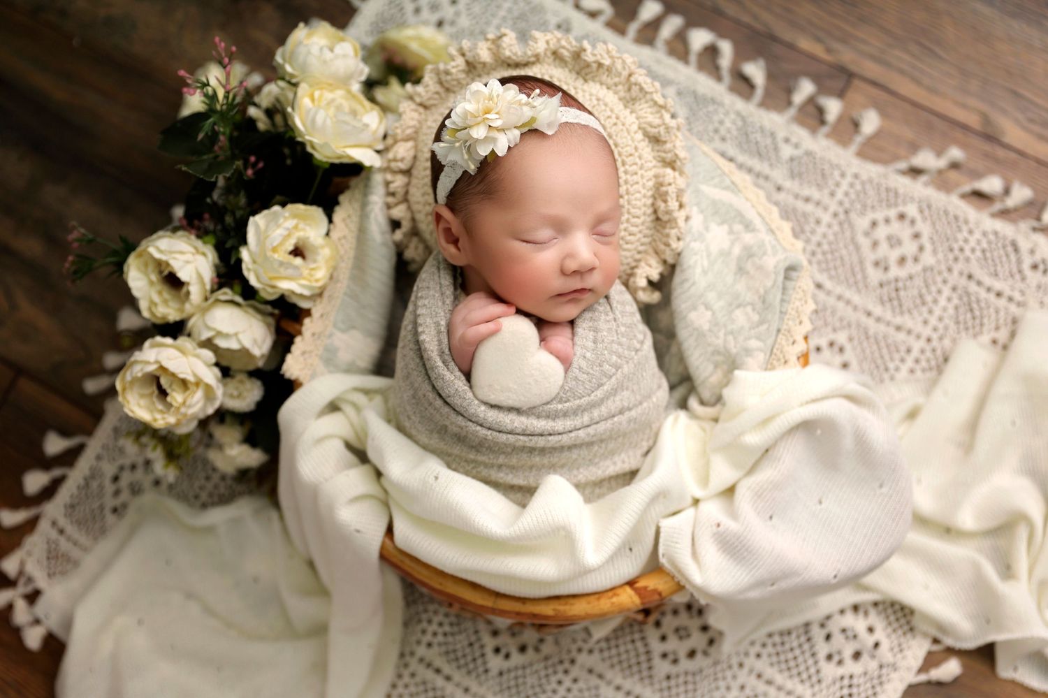 Vintage-styled newborn photography scene with delicate lace, white flowers, and soft textures.