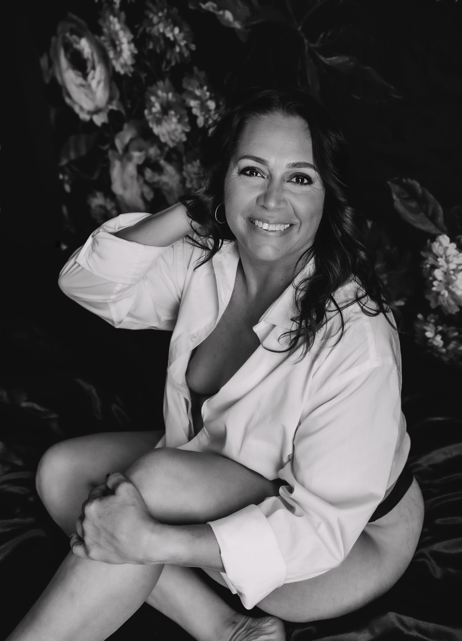 a woman sitting on a bed smiling during her boudoir photoshoot in tampa florida