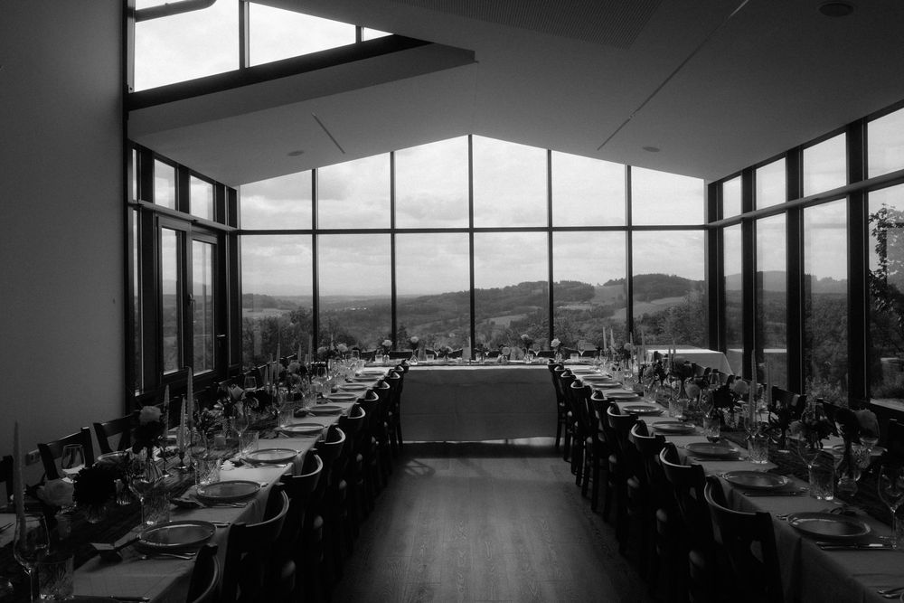 Black and white photo of a stunning wedding reception hall with floor-to-ceiling windows and mountain views.