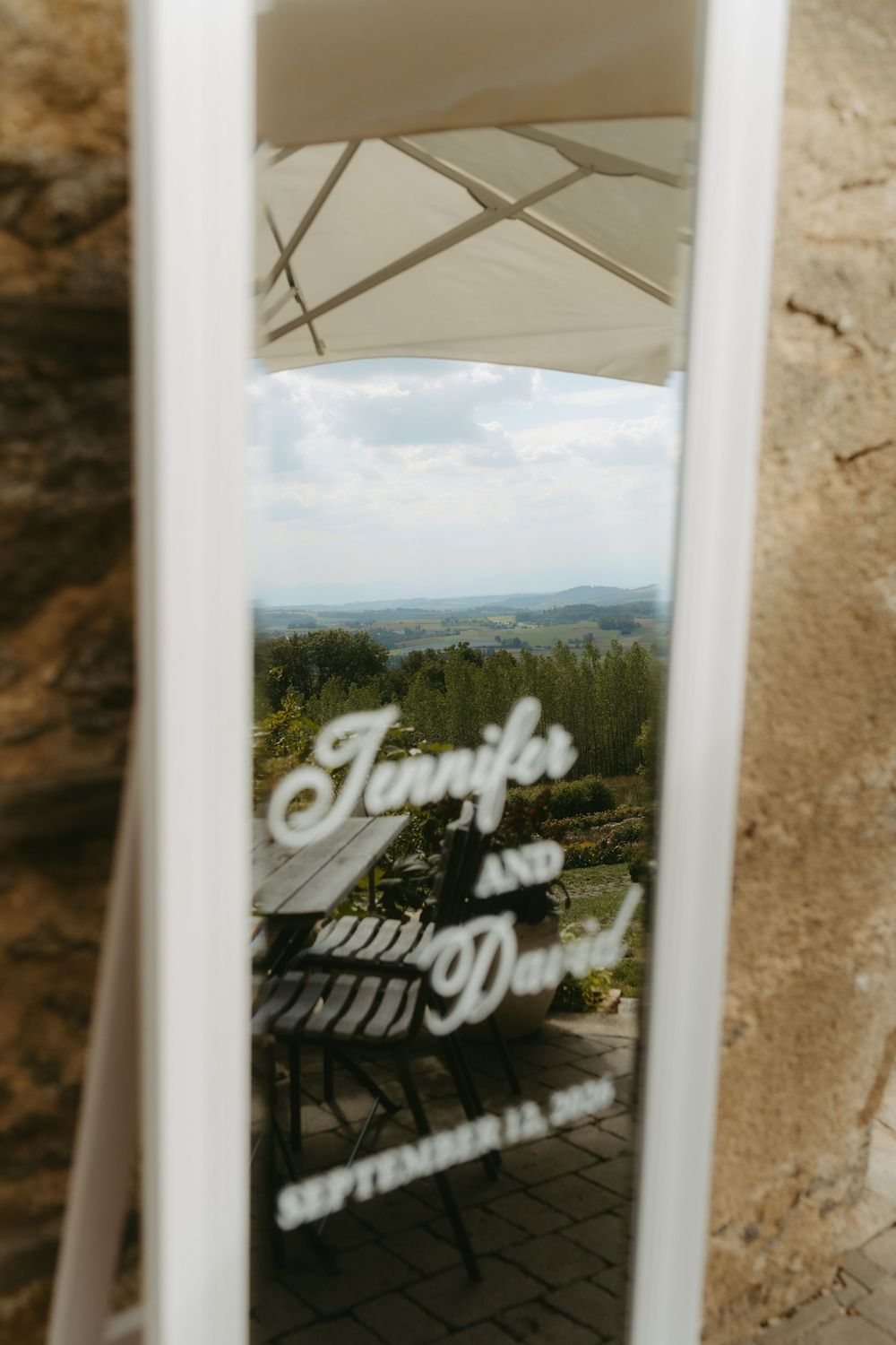 Mirror reflection of Jennifer and David September wedding sign with scenic rolling hills landscape backdrop.