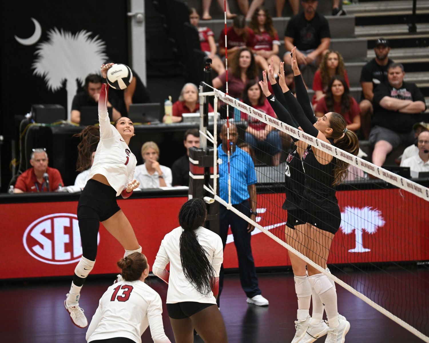 South Carolina volleyball hitter attacks the ball against a blocker at the net.
