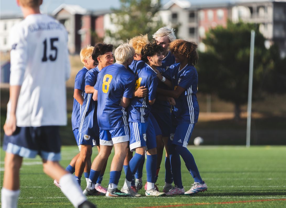Soccer players in blue uniforms gathering for a team celebration during a match.