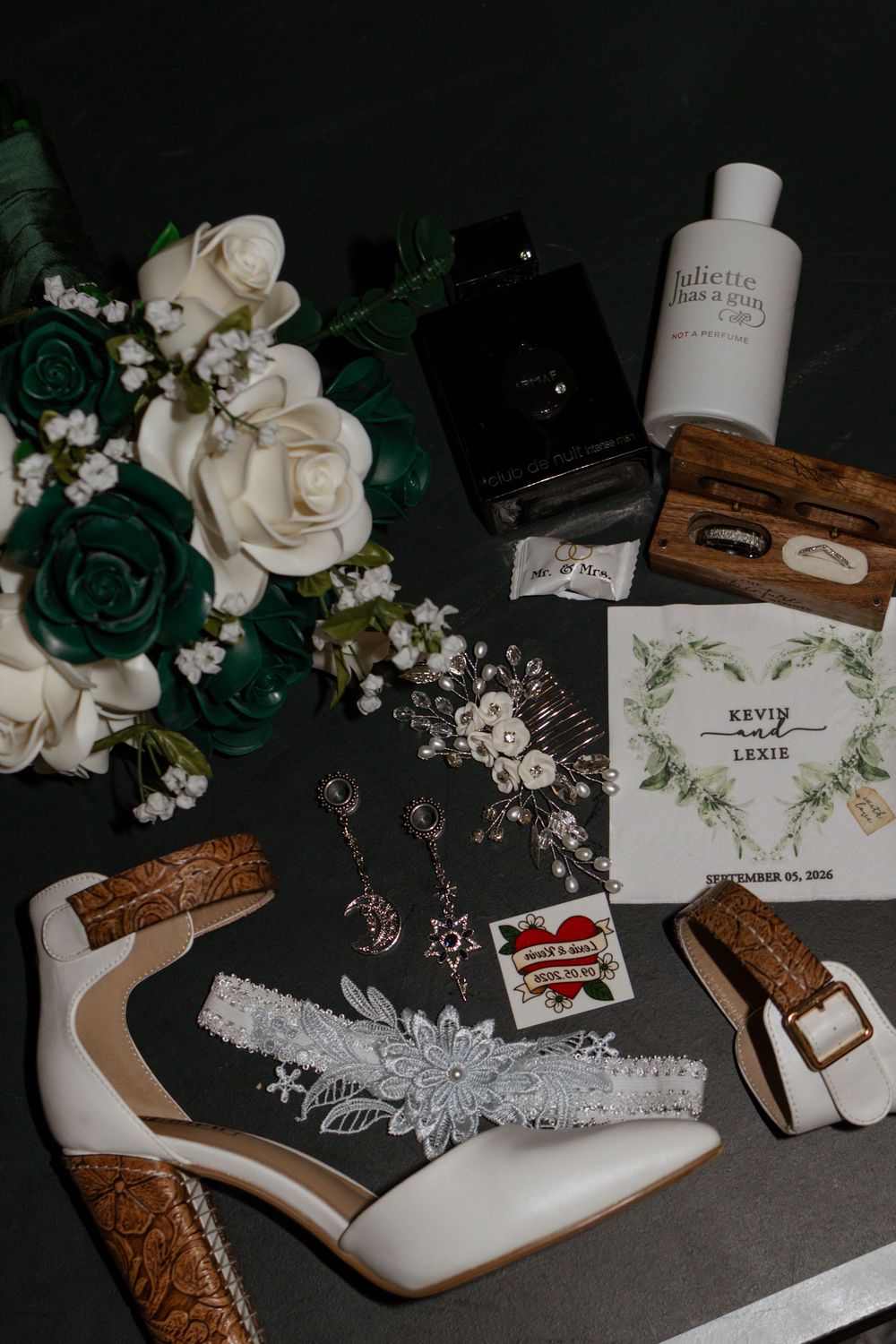 Wedding flat lay featuring white heels, floral bouquet, garter, rings, and accessories for Kevin and Lexie's December wedding.