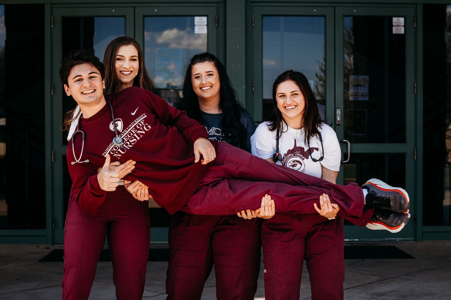 Fairmont State Universty Graduates Seniors Pose In Front Of The Falcon Center.