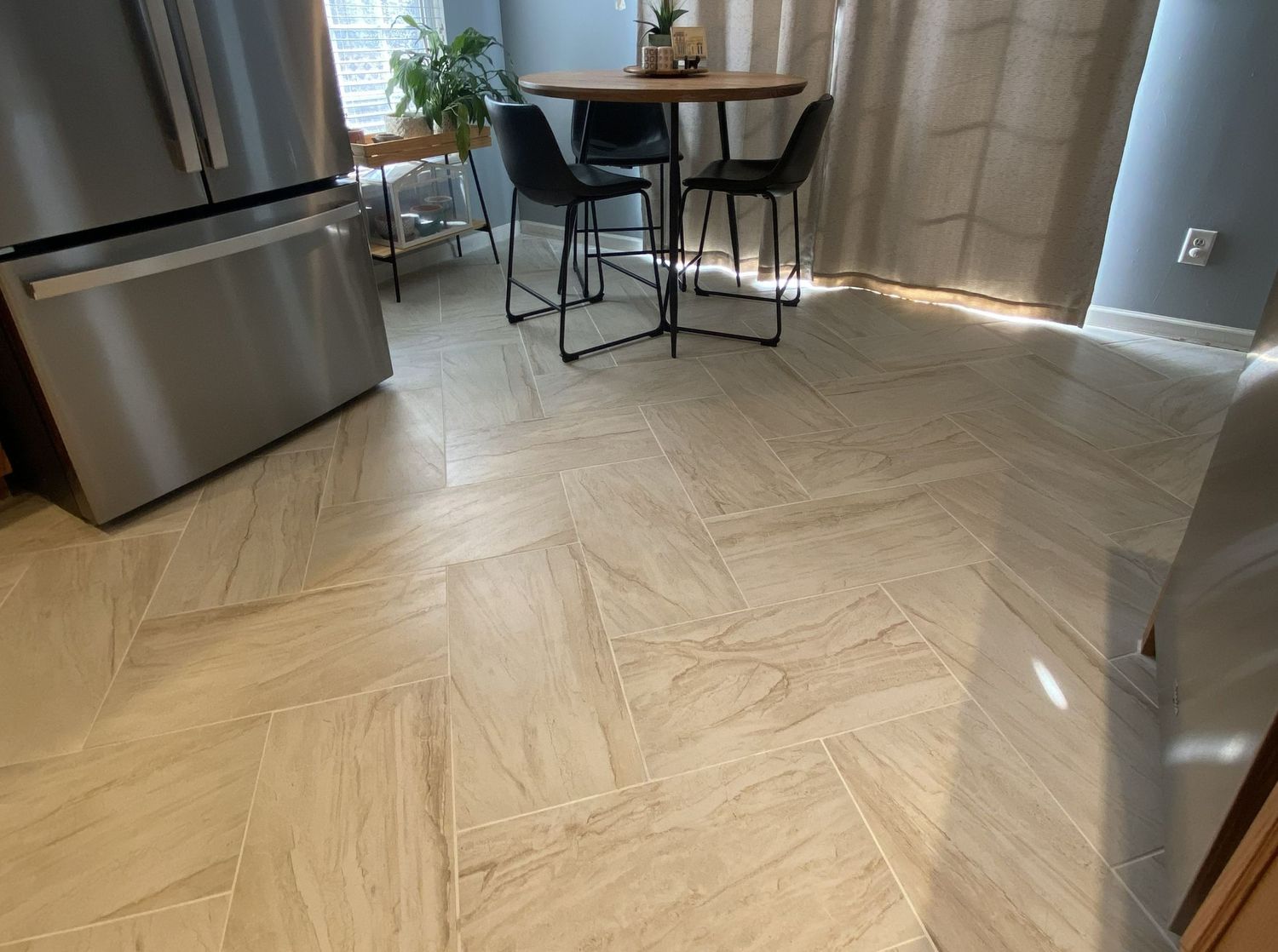 Light beige herringbone pattern tile floor in a bright kitchen and dining room space.