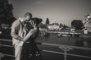 Black and white photo of a couple sharing a romantic moment on a bridge over a canal in Leiden at dusk.