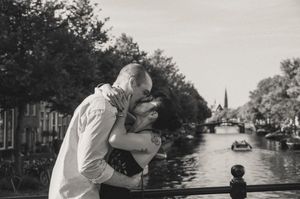 Couple sharing a romantic kiss on a bridge over an Leiden canal in black and white photography.