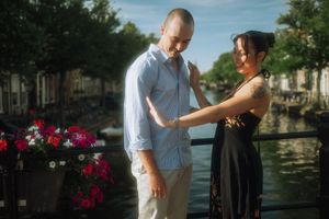 Couple sharing a romantic moment on a bridge over an Amsterdam canal surrounded by flowers.