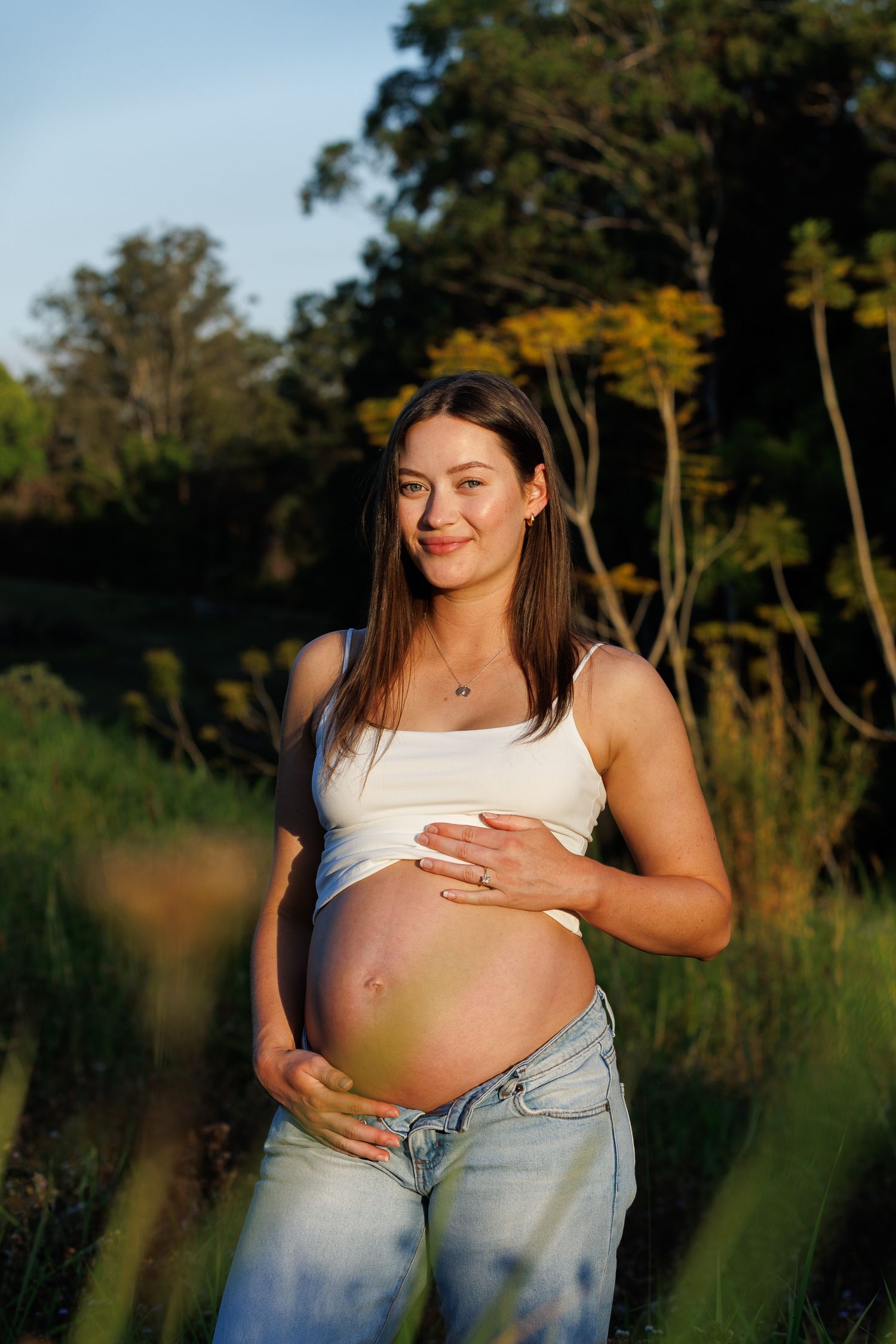 pregnant lady posing on a rural property at golden hour