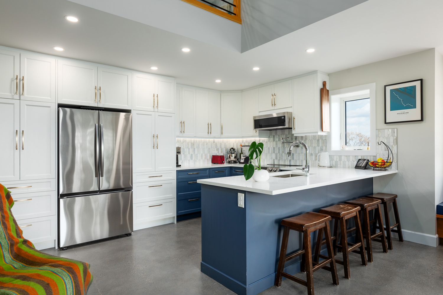 Bright renovated kitchen with white cabinets and a blue island in Thorncliffe, Calgary — from a real estate video by RezinMedia