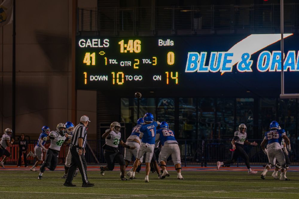 Football players in blue and white uniforms line up on the field beneath a scoreboard showing Gaels 41, Bulls 0 in the third quarter.