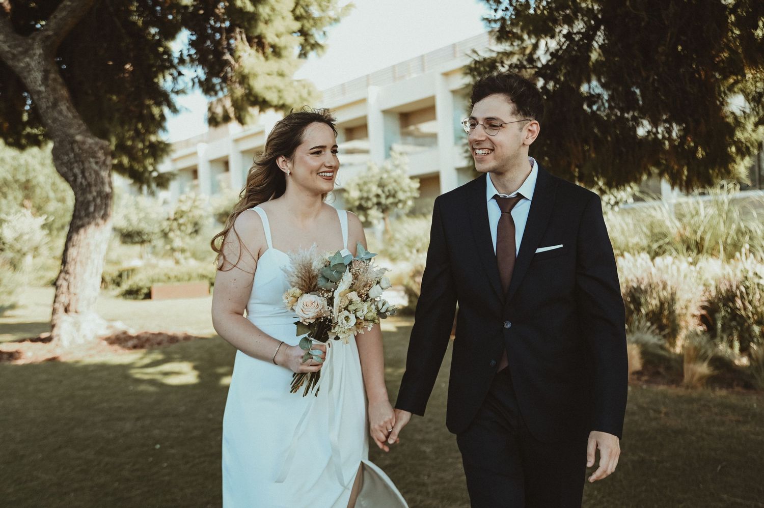 Black and white wedding photo of bride and groom gazing at each other outdoors among trees.