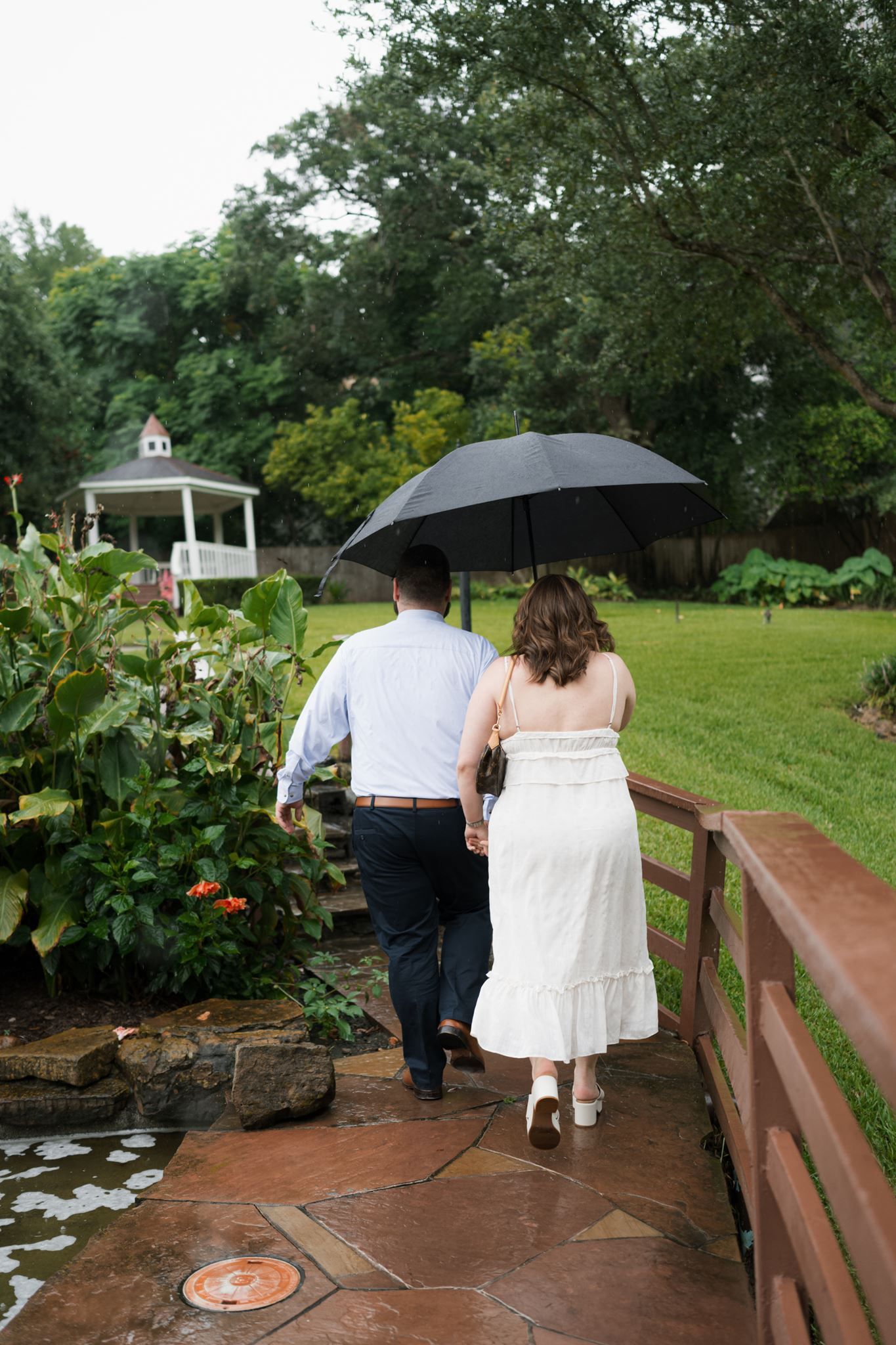 Couple walking through the gardens after their rainy-day Houston proposal
