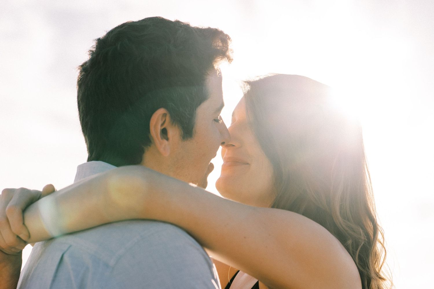 Sunlit close-up of couple embracing during golden hour photoshoot.