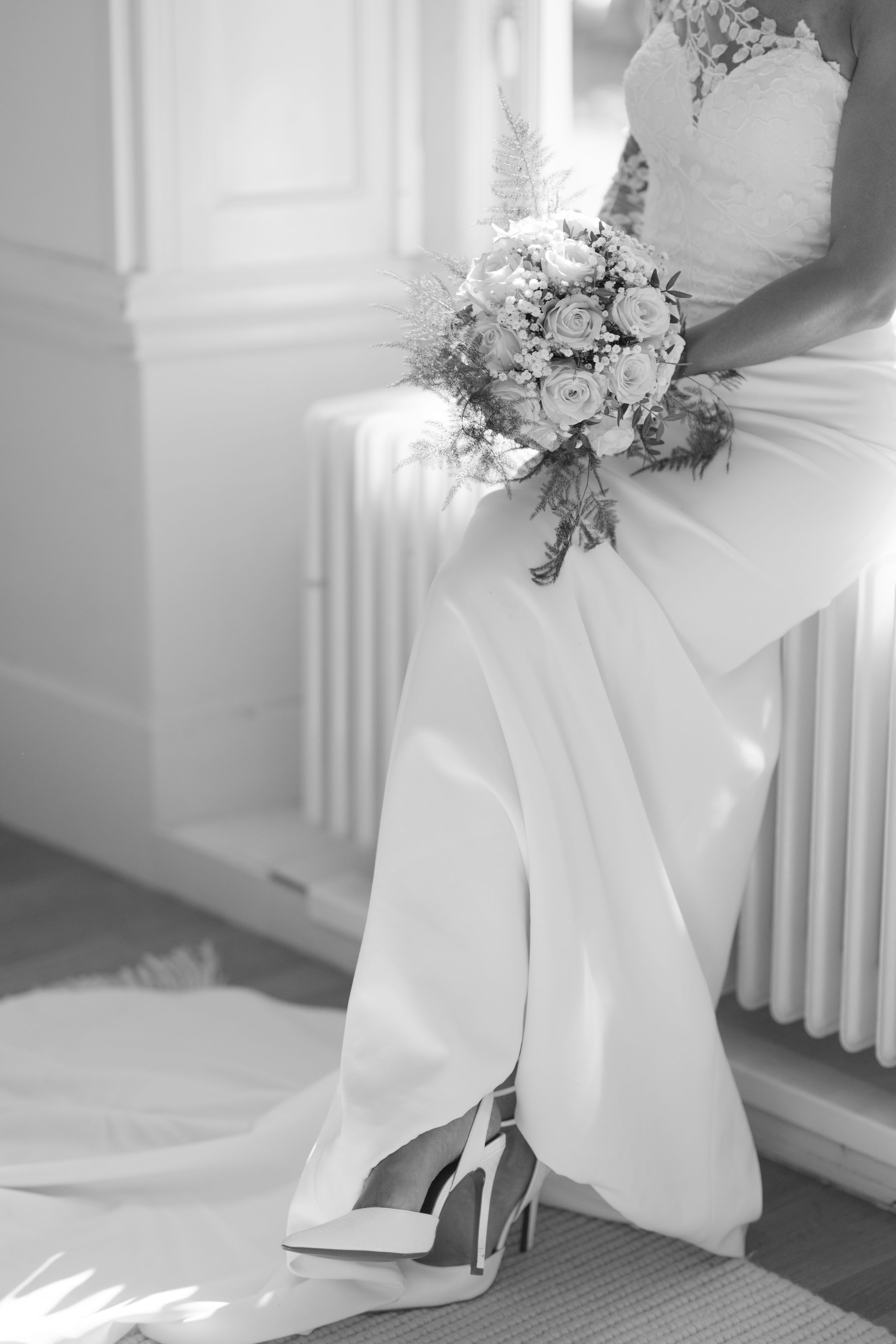 Elegant wedding details featuring white dress, bouquet and heels in natural light.