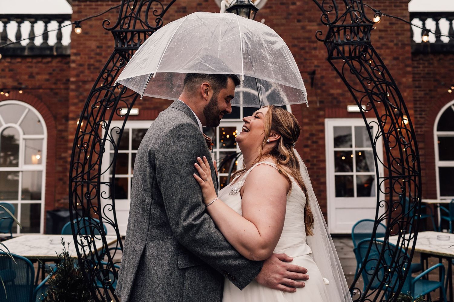 A couple sharing an intimate moment under a clear umbrella during their wedding ceremony.