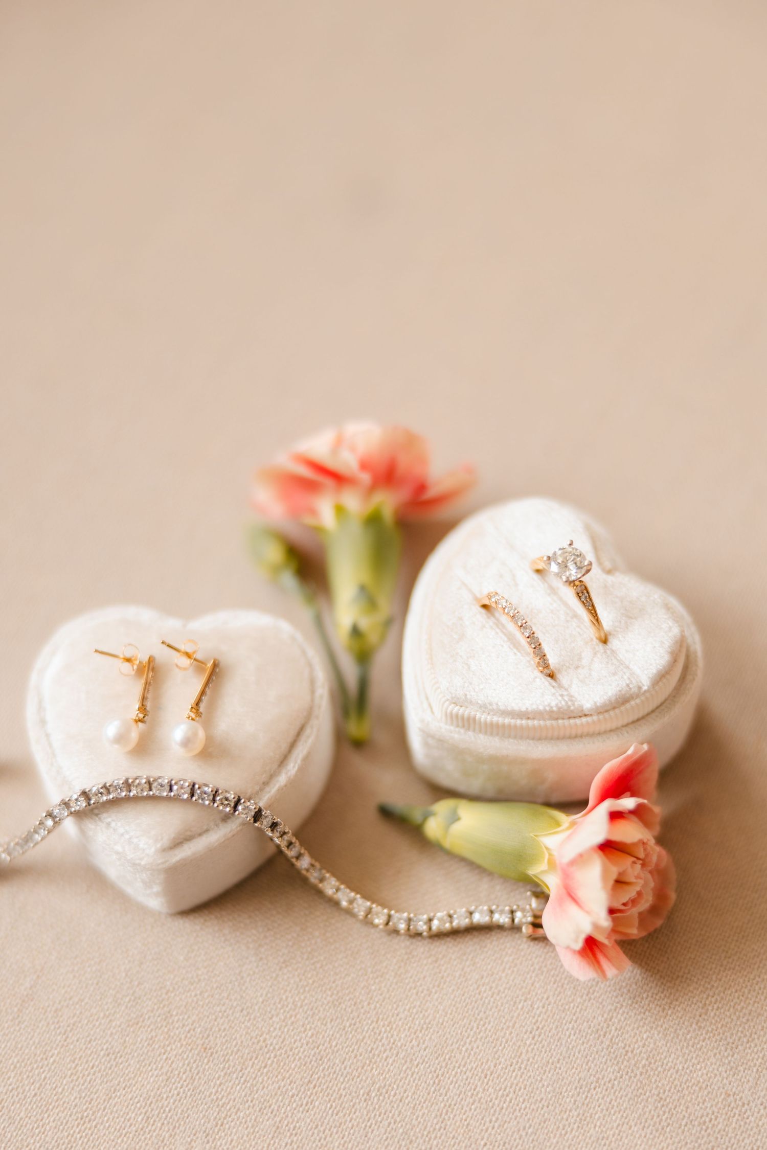 Gold bridal jewelry set with diamond ring, pearl earrings, and bracelet on heart-shaped velvet boxes.