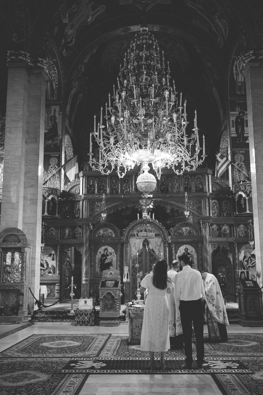 Black and white photo of Orthodox church interior with grand chandelier and traditional iconostasis.