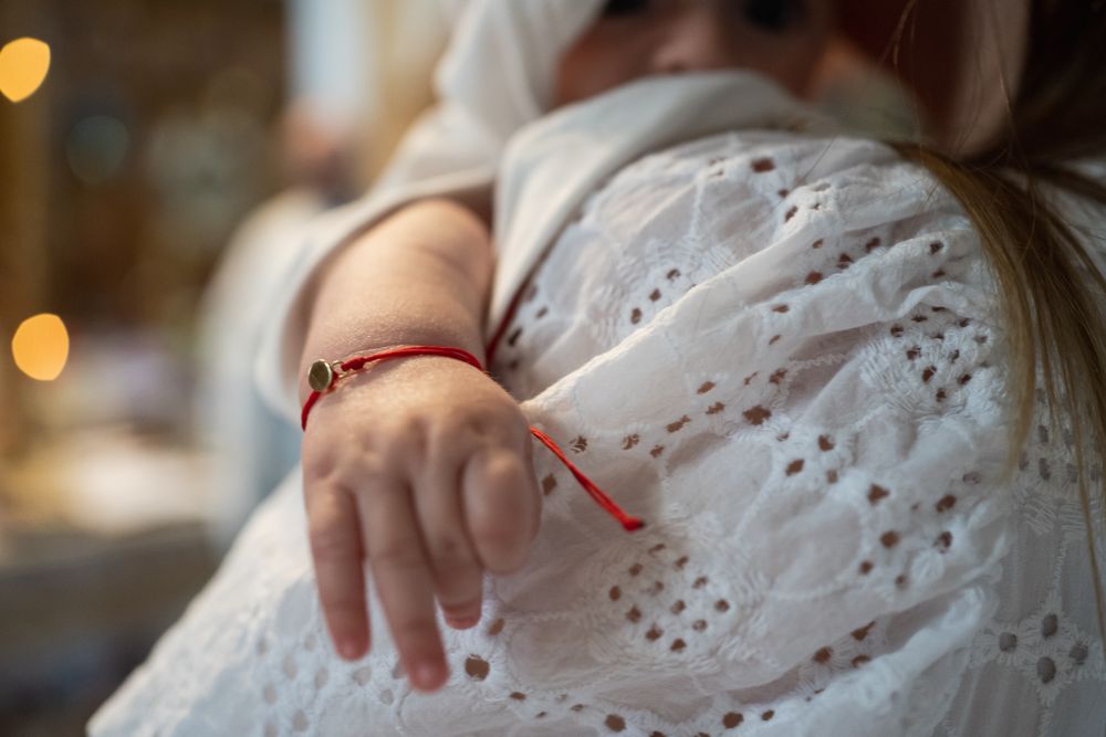 Detail shot of white eyelet lace dress during a religious ceremony.