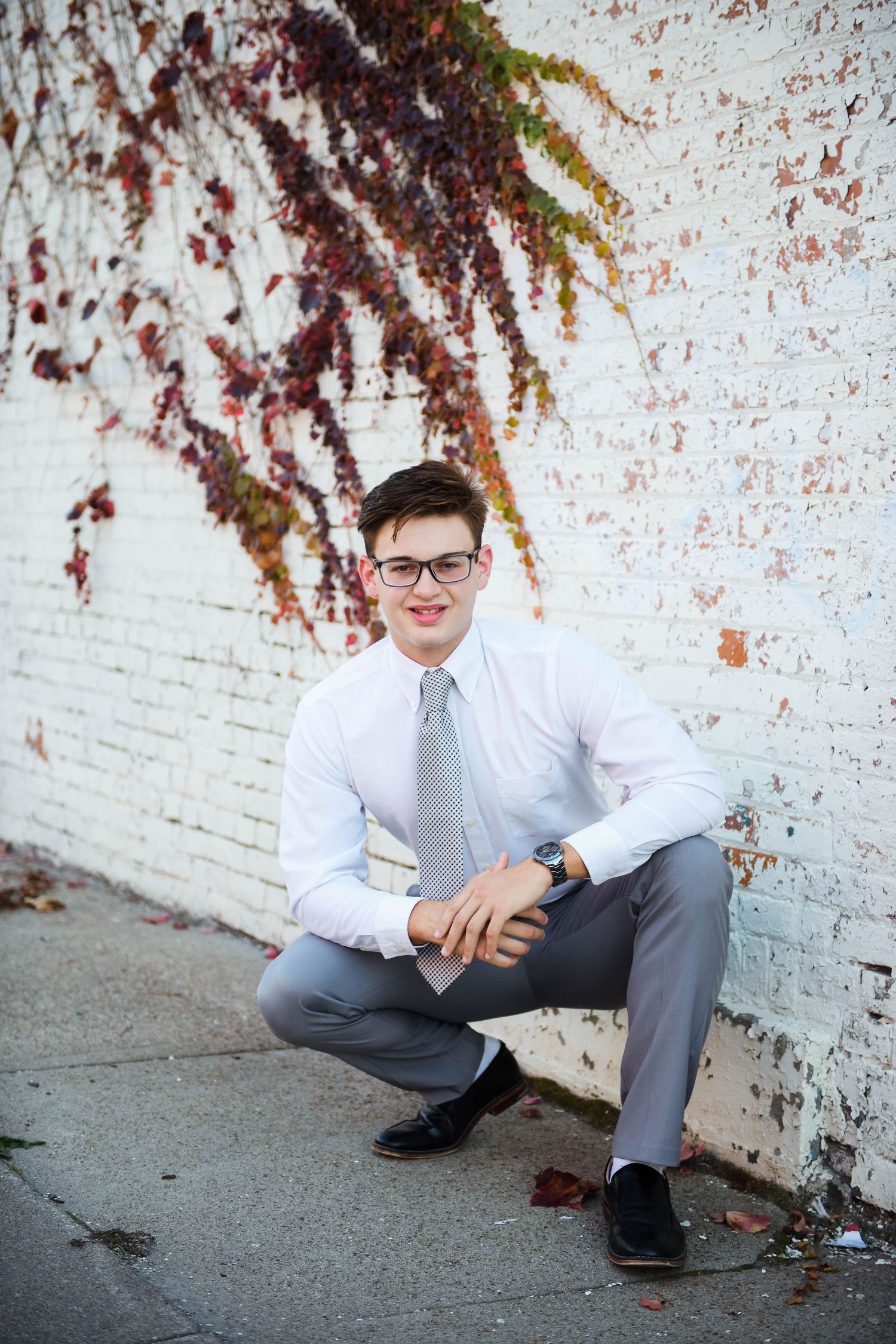 senior boy wearing a suit by a white wall
