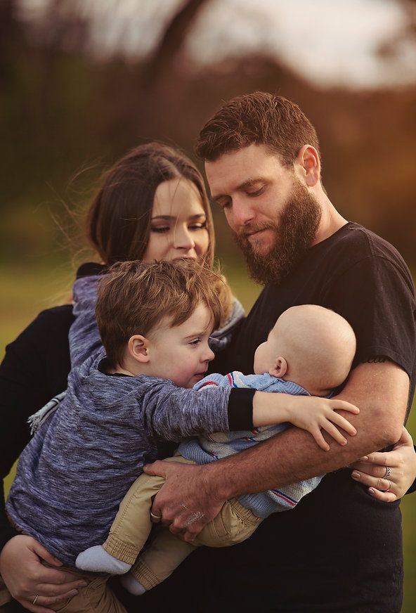 Kaitlyn, Joshua, Liam and Fletcher cuddling together all looking at the baby