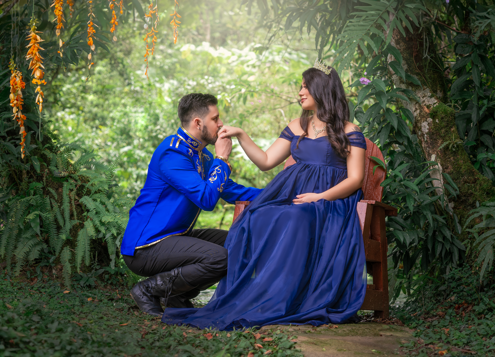 A fairytale-inspired maternity scene with royal blue dress in a lush garden setting.