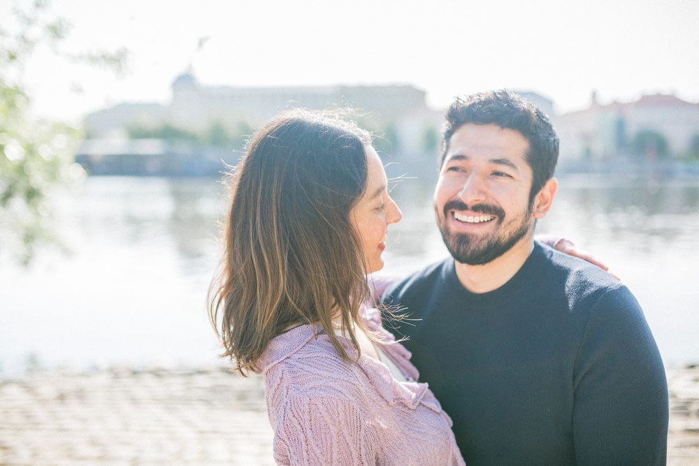 A couple sharing an intimate moment by the waterfront on a sunny day.