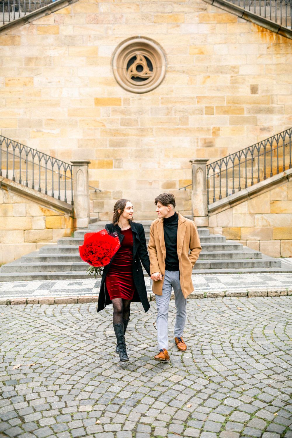 Couple walks together outside historic stone building with unique architectural details.