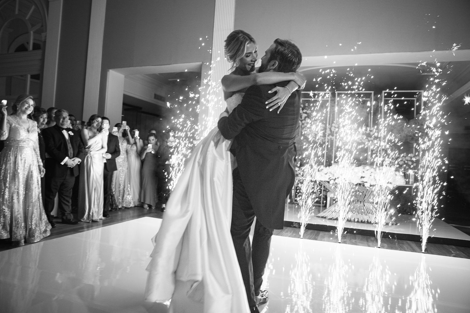 A newlywed couple shares their first dance surrounded by sparklers and wedding guests.