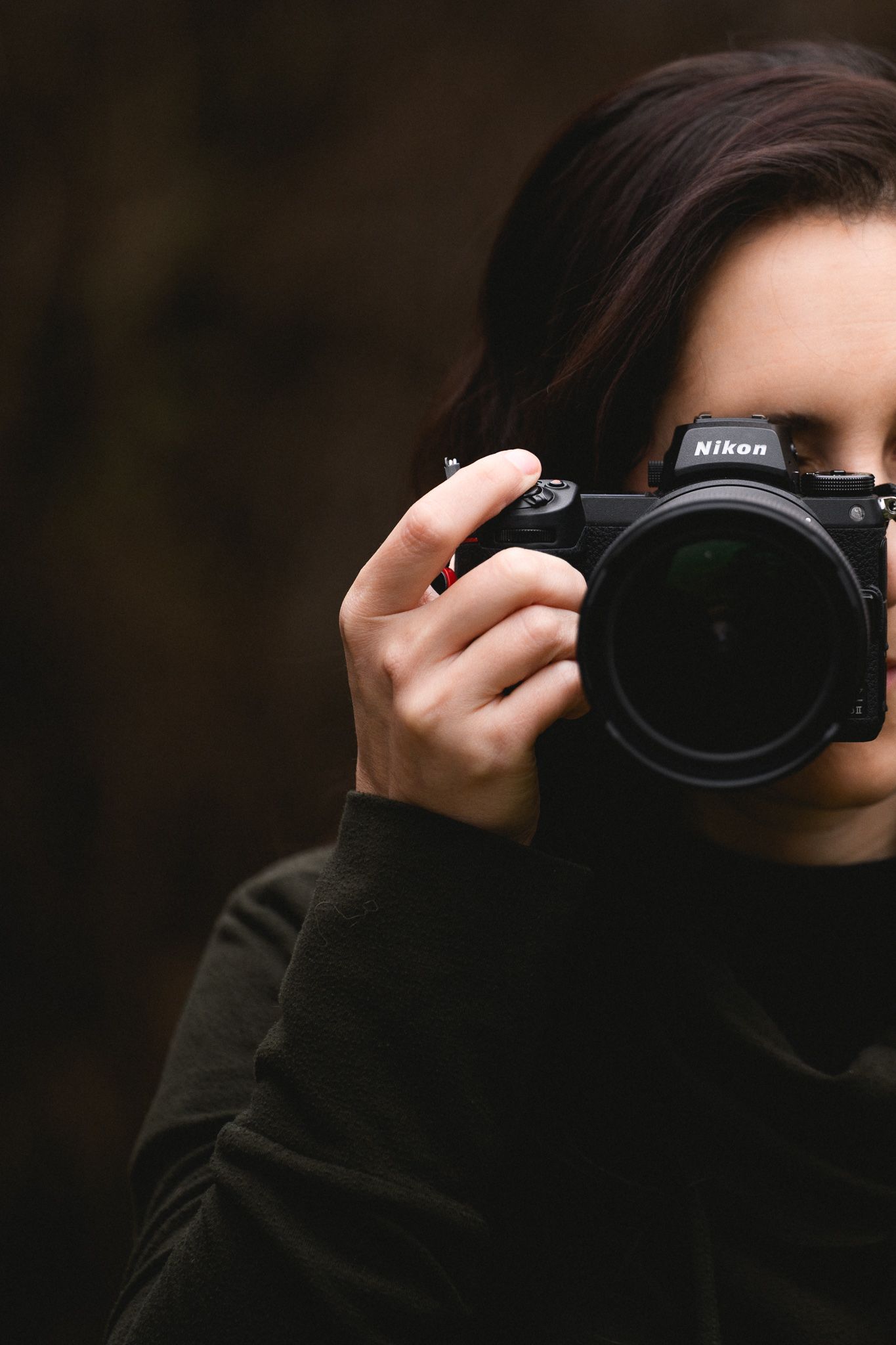 Female photographer holding Nikon camera up to her eye taking a photo.