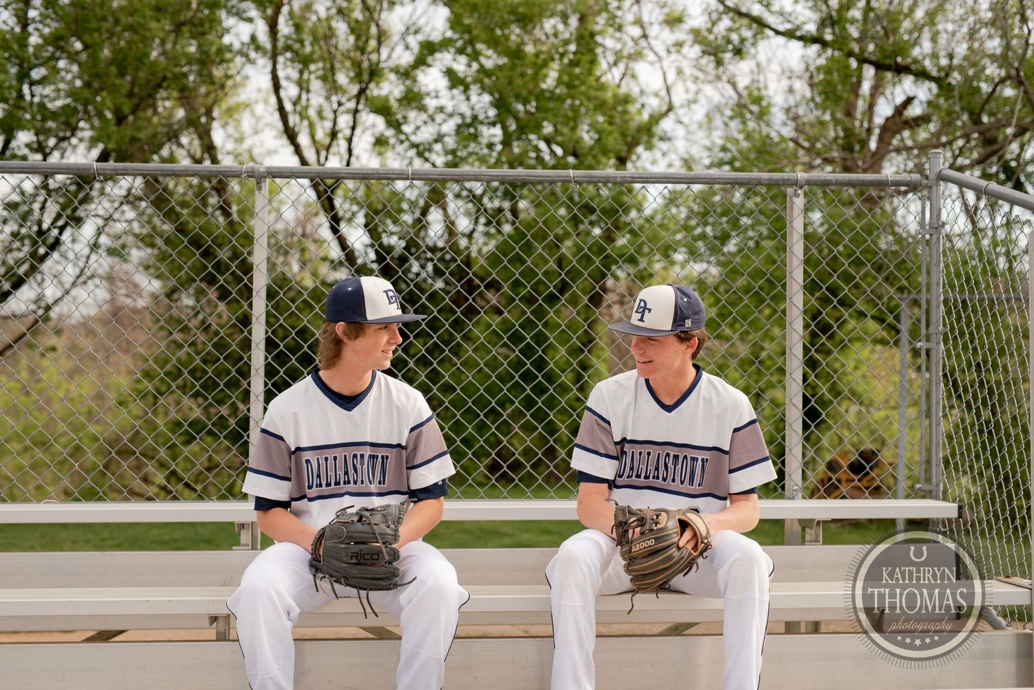 Baseball players sitting on bleachers having conversation during game break.