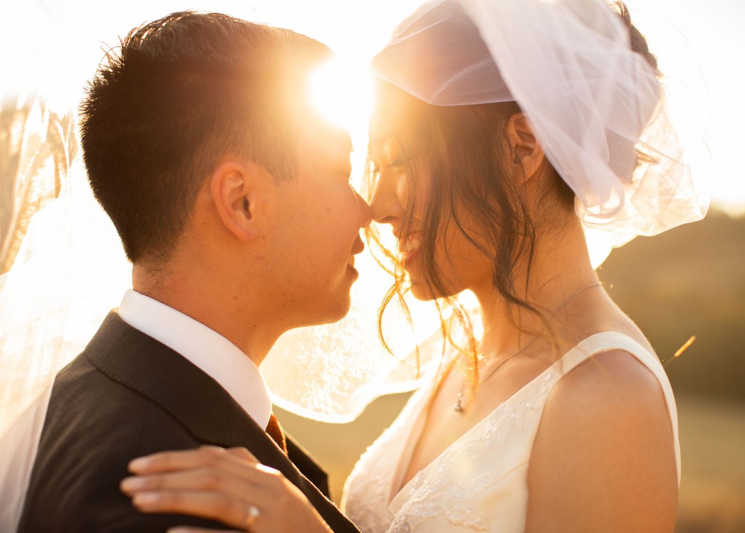 A bride and groom share an intimate moment at sunset with golden light streaming between them.