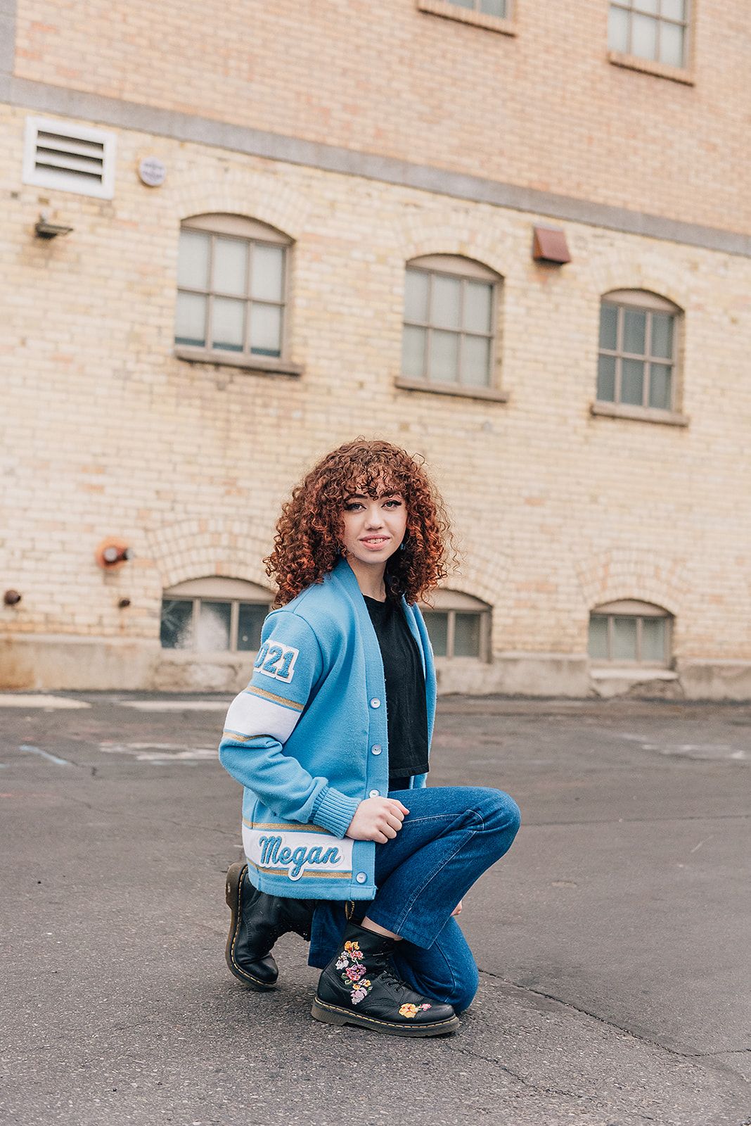 Casual portrait against brick building wearing light blue jacket and jeans.