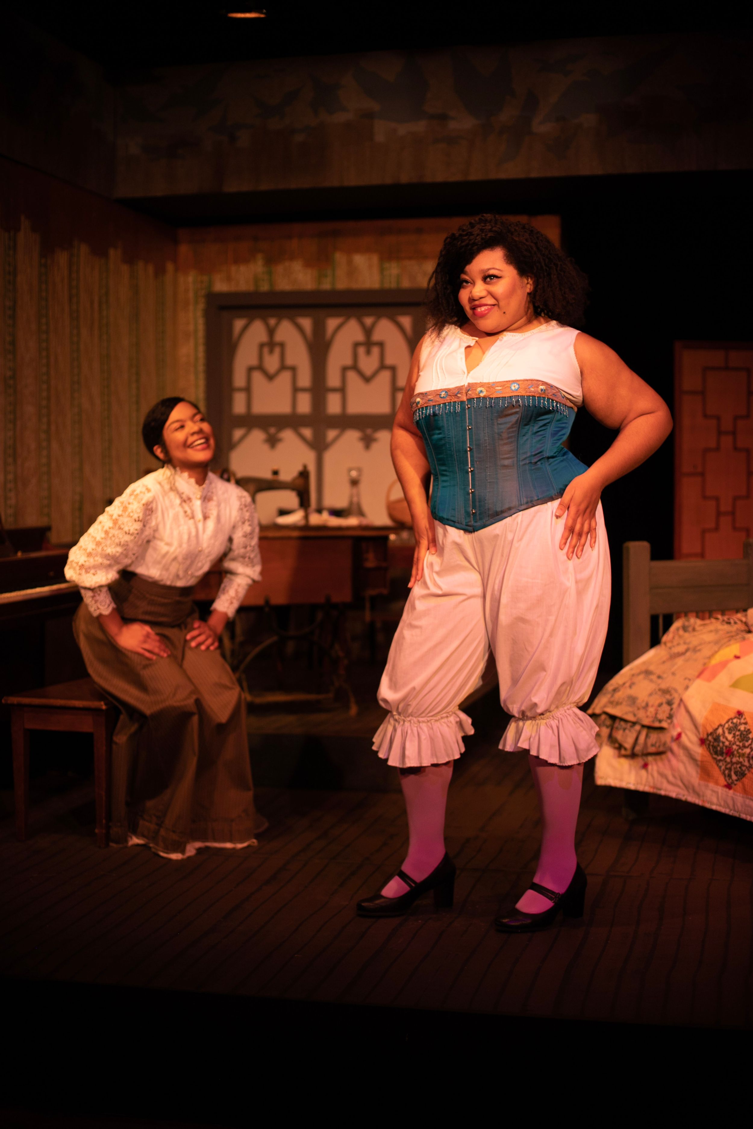 Two performers in Victorian-era costumes act out a comedic scene on stage.