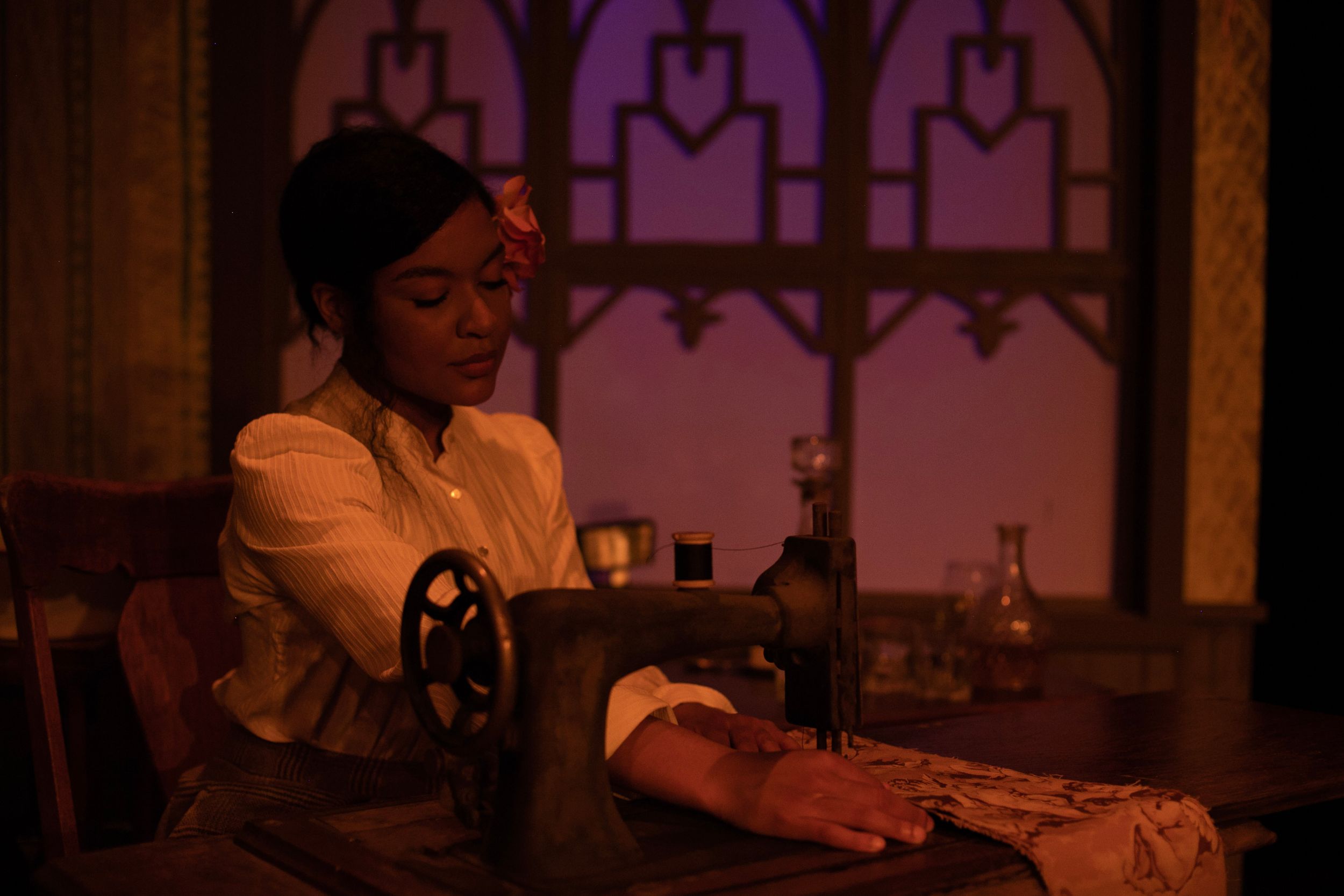 Dimly lit atmospheric scene in vintage tavern setting with purple stained glass windows.