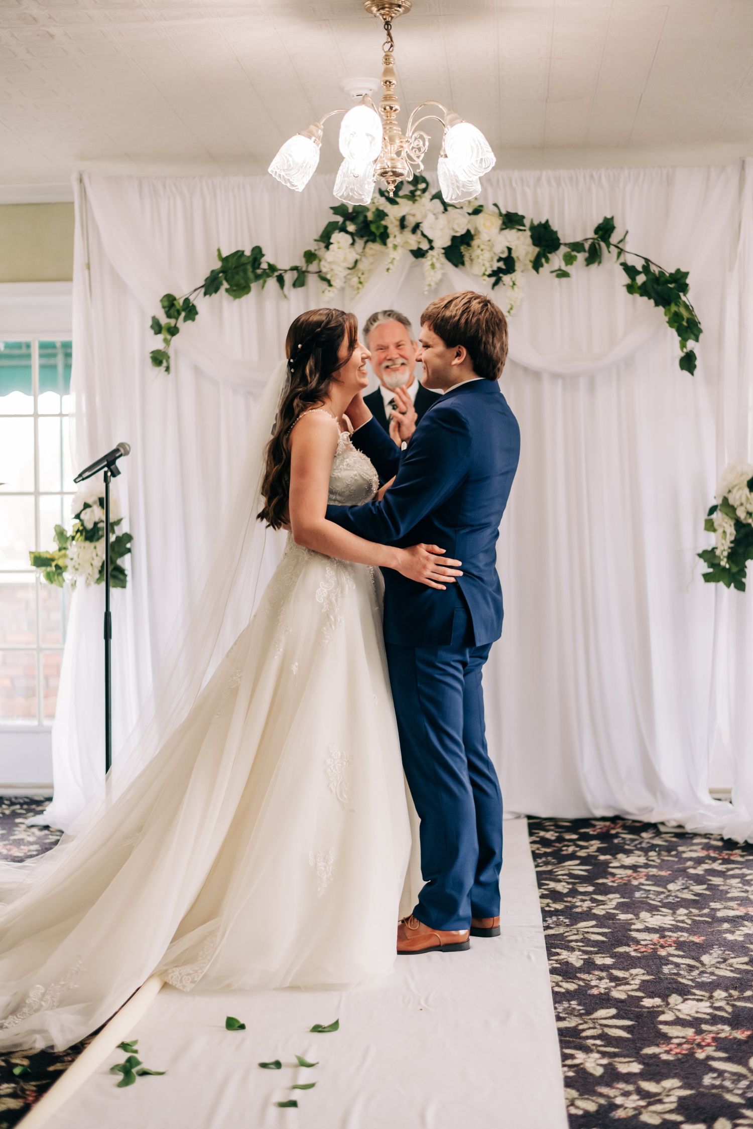 bride and groom smiling at each other, officiant clapping at wedding ceremony