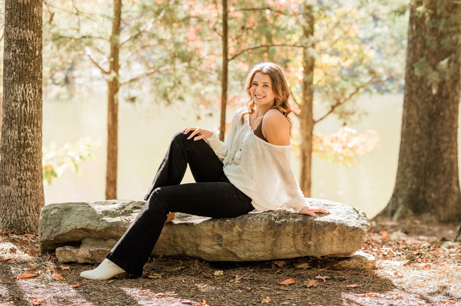 Natural outdoor setting with large tree trunks and scattered autumn leaves.