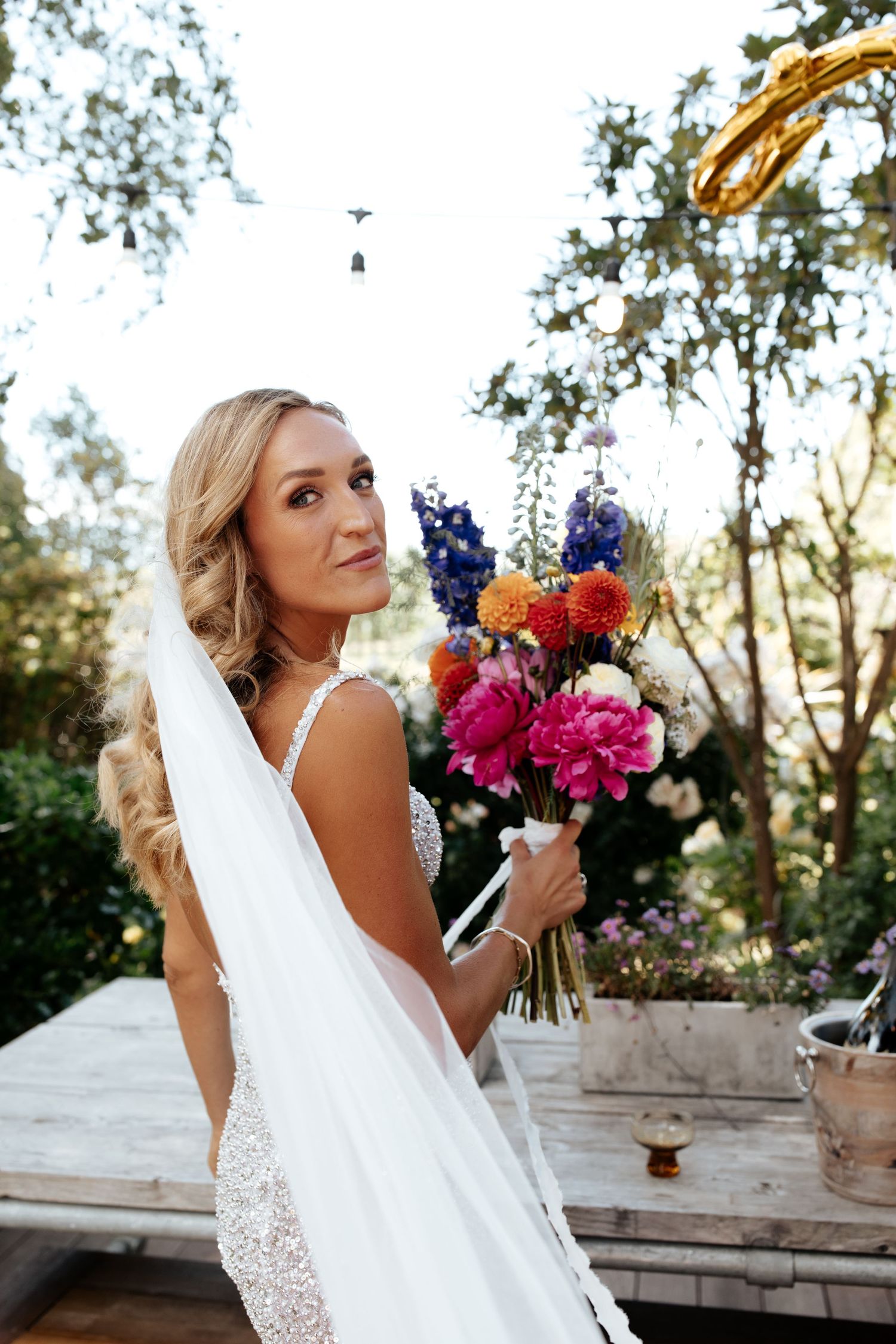 Outdoor bridal portrait with colorful wildflower bouquet and flowing veil.