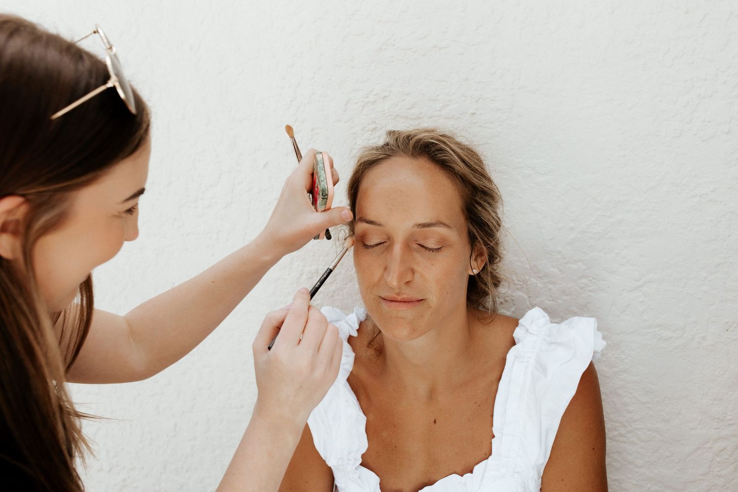 Wedding makeup artist applying cosmetics to client before the ceremony.