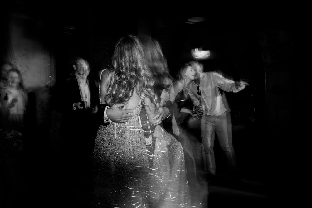 Black and white photo of people dancing at a party with motion blur effects.