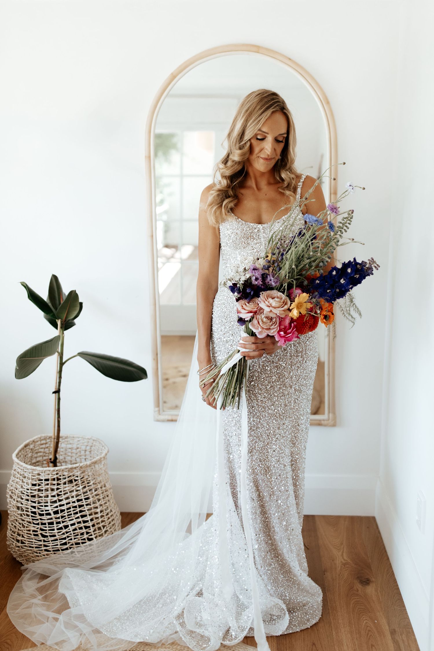 Full length mirror reflection showing sparkly wedding dress and colorful bouquet.