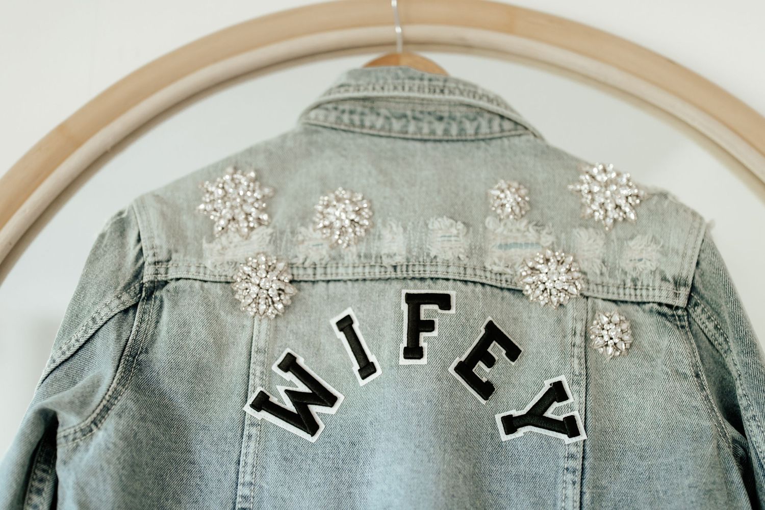 Light denim jacket customized with 'WIFEY' text and decorative white snowflake embellishments.