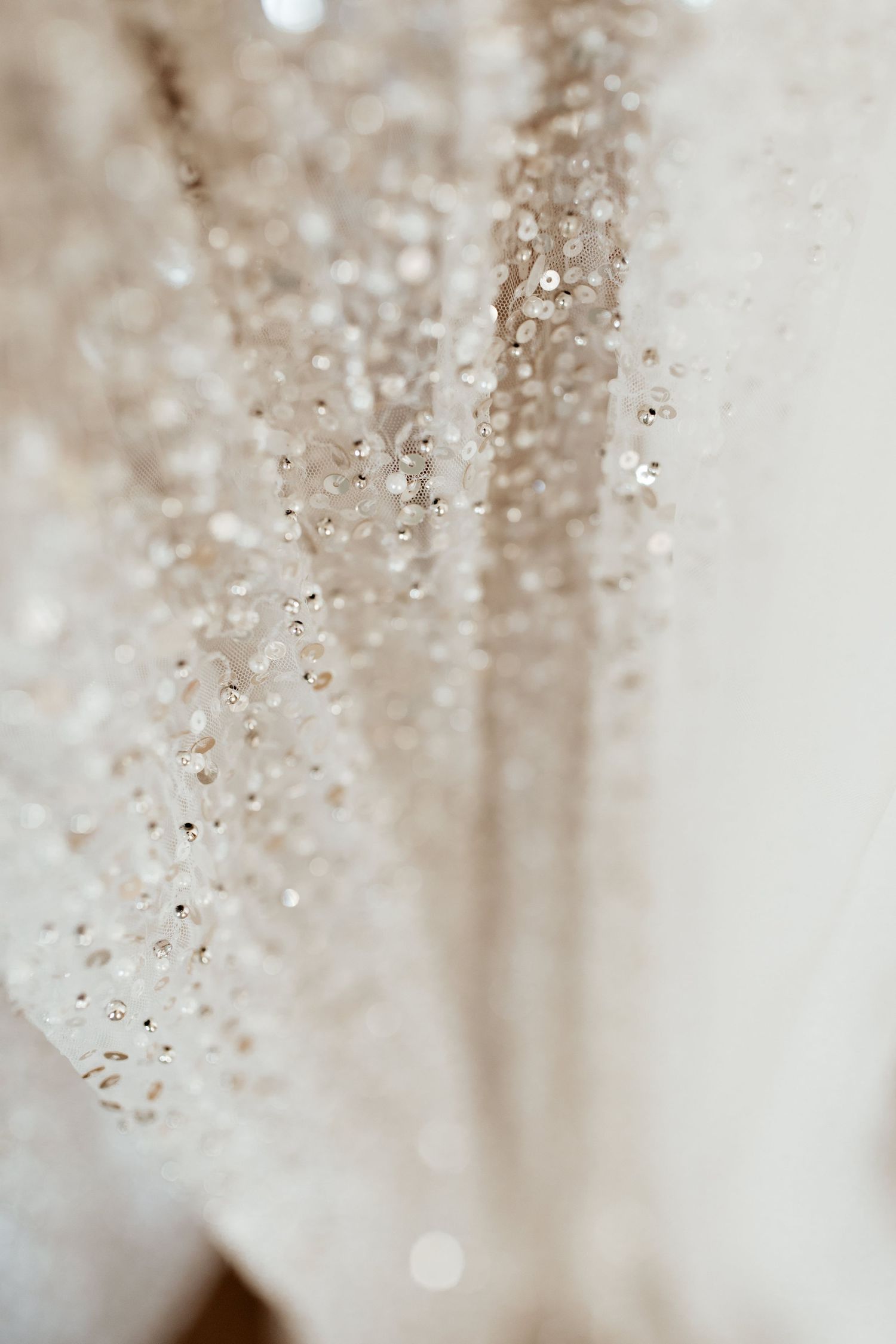 Close-up macro shot of sparkling sequins and beading details on wedding dress fabric.