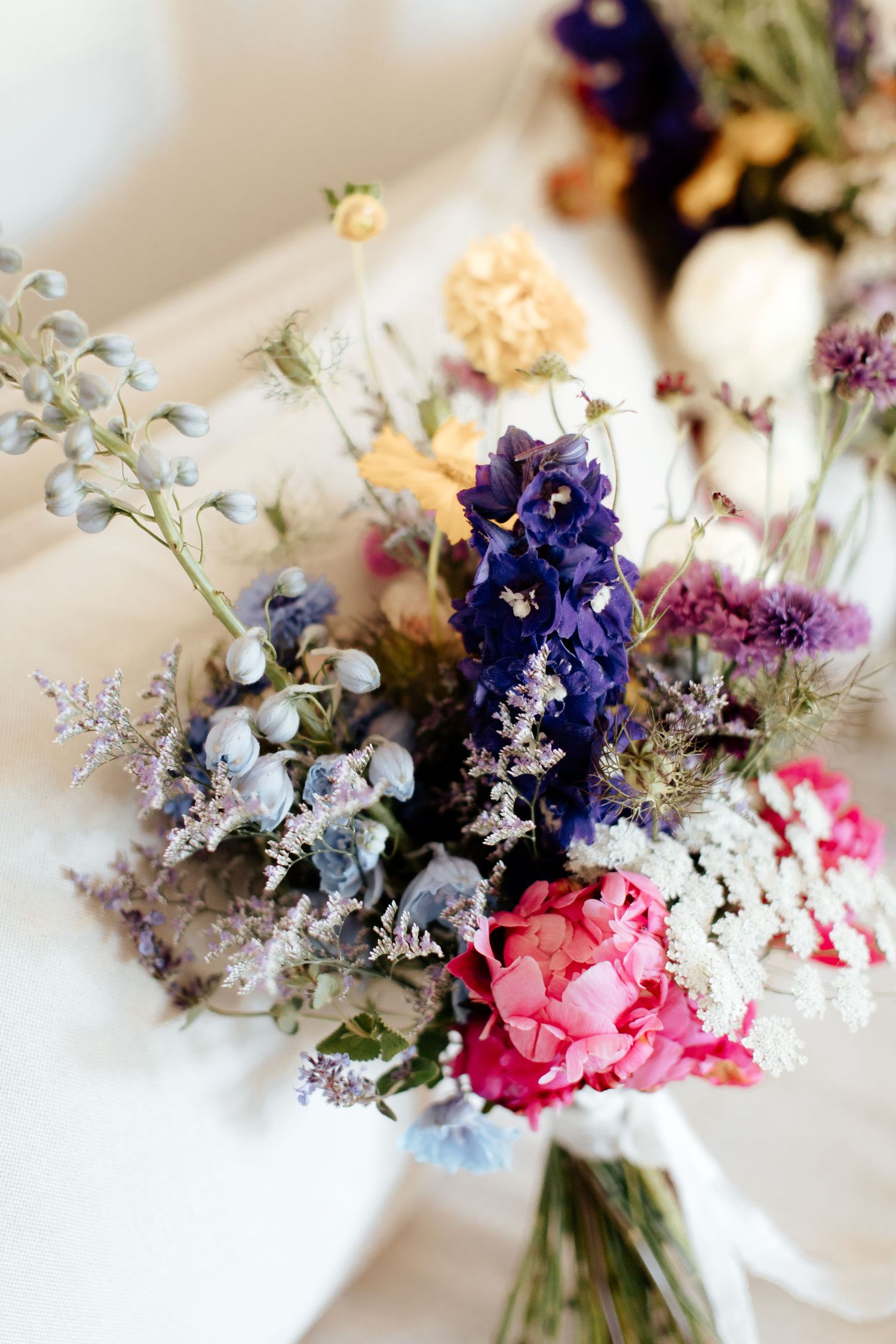 Romantic wedding bouquet with purple, pink and white wildflowers tied with ribbon.