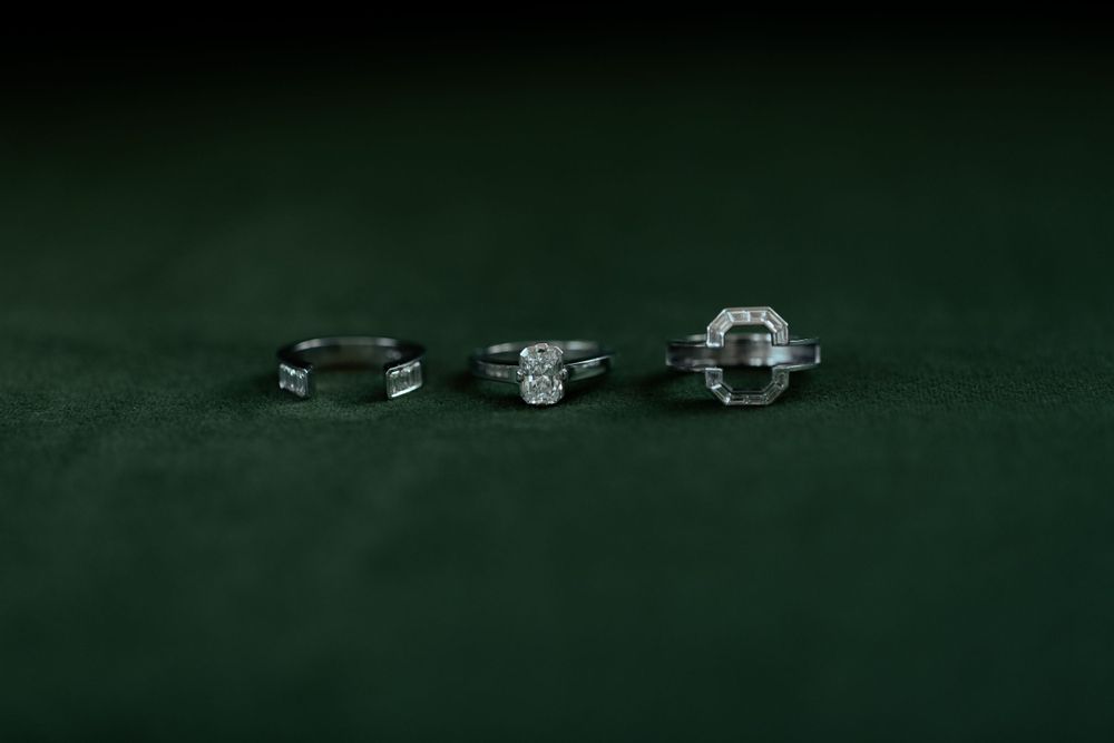 Three diamond engagement rings lined up on dark green velvet background.
