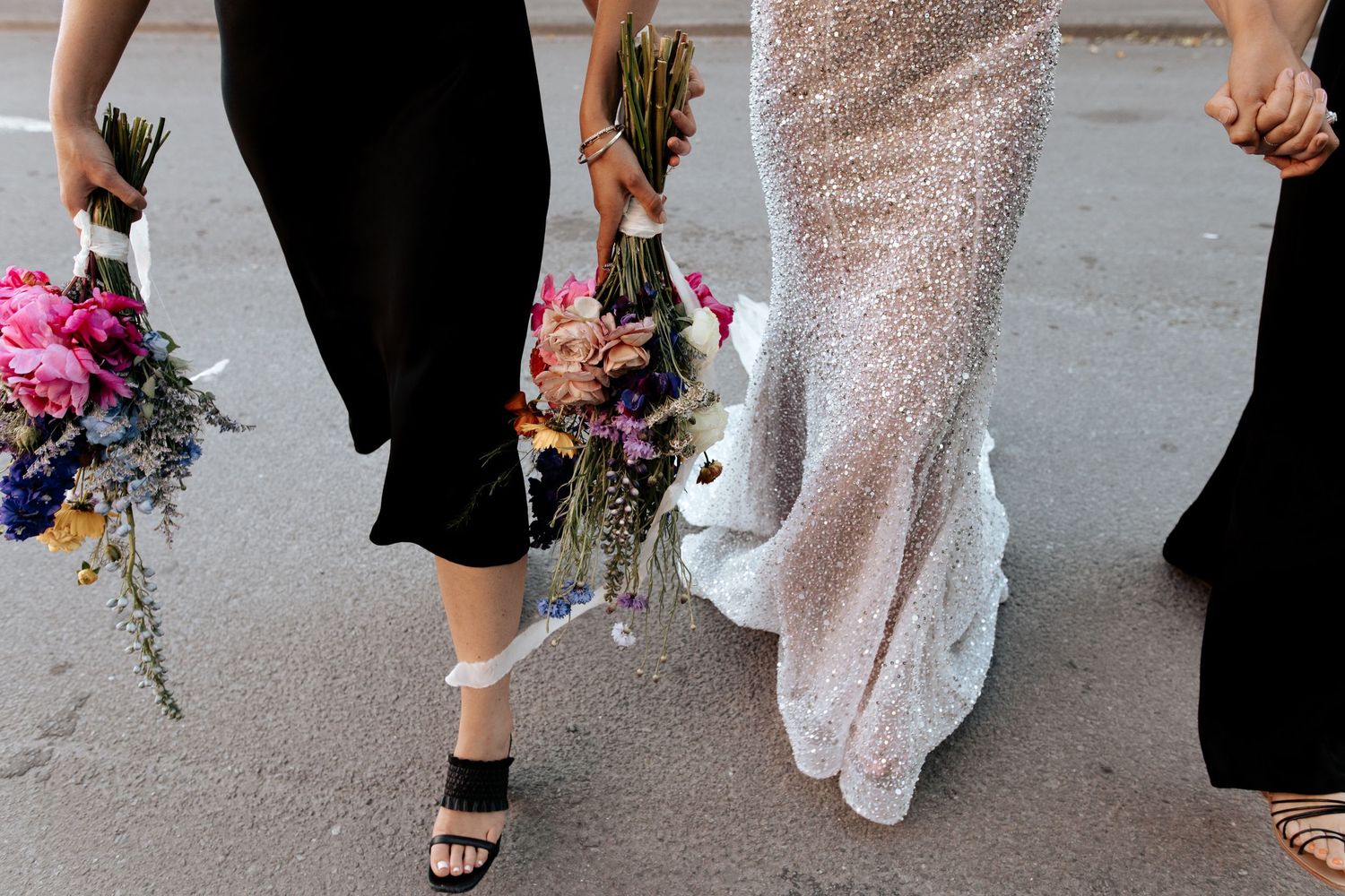 Detail shot of women's feet and dresses as they walk, showing black and sparkly white gowns.