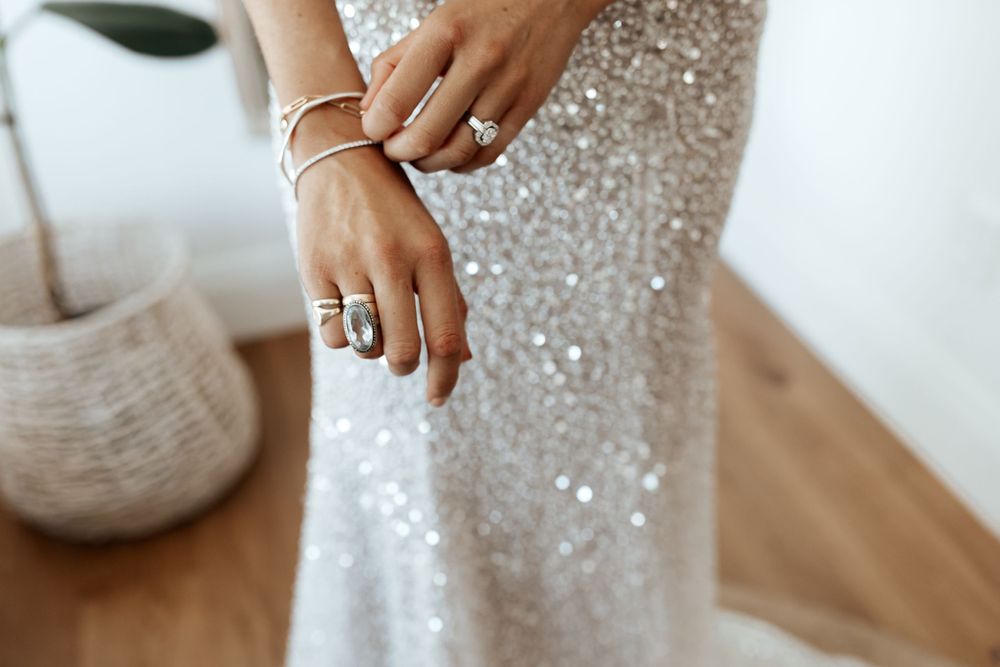 Close up of sparkling sequin wedding dress fabric with jewelry details.