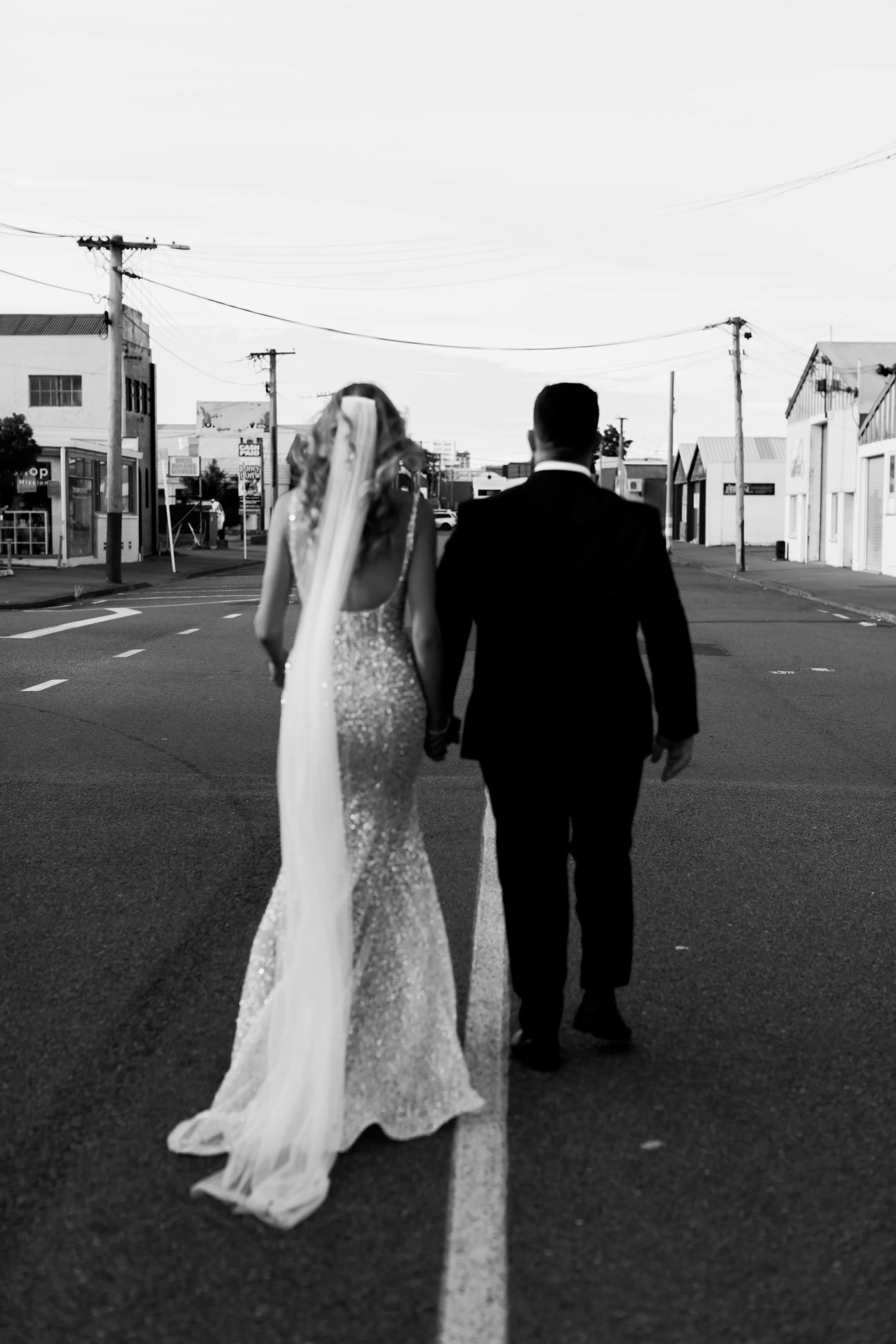 Black and white photo of newlyweds walking down an empty street.