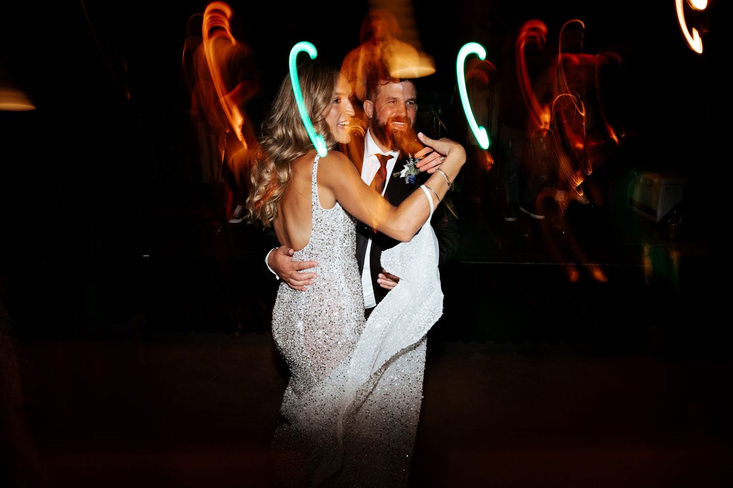 Couple sharing an intimate dance moment with colorful neon lights in the background.