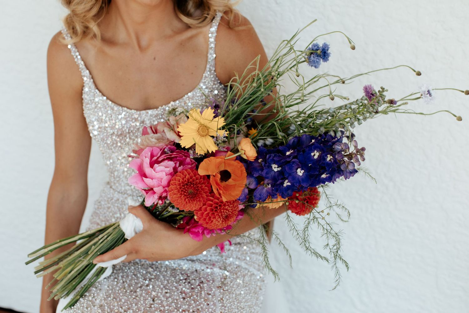 Close up of wildflower bridal bouquet with bright pink, blue and yellow blooms.
